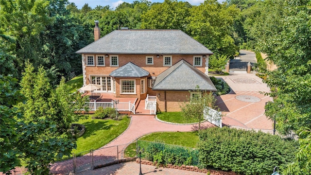 view of front of home with driveway, a chimney, fence, a front yard, and brick siding