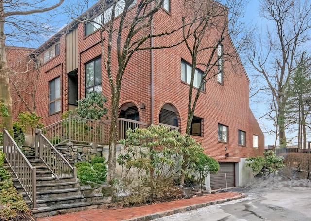 view of property featuring an attached garage, driveway, and stairs