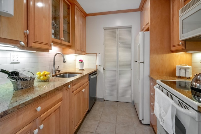 kitchen with light tile patterned floors, white appliances, a sink, ornamental molding, and light stone countertops