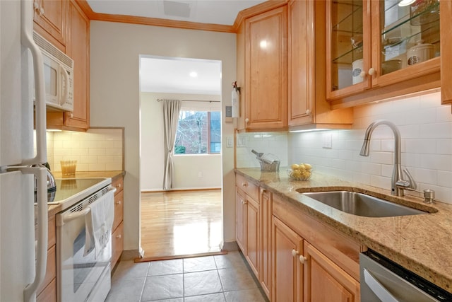 kitchen featuring white appliances, a sink, ornamental molding, light stone countertops, and glass insert cabinets