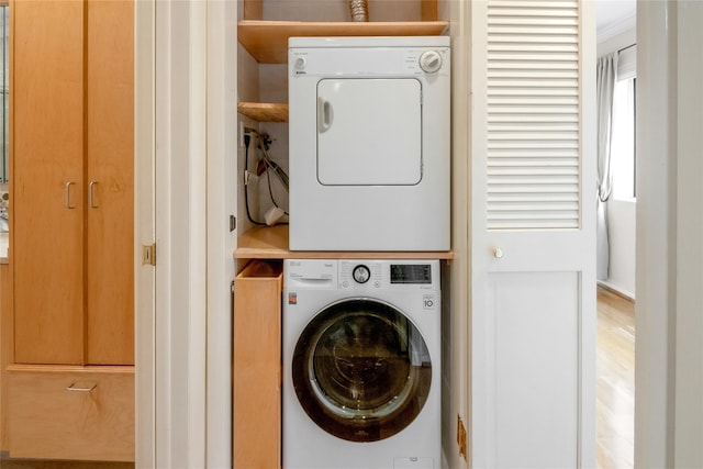 clothes washing area featuring stacked washer / dryer and laundry area