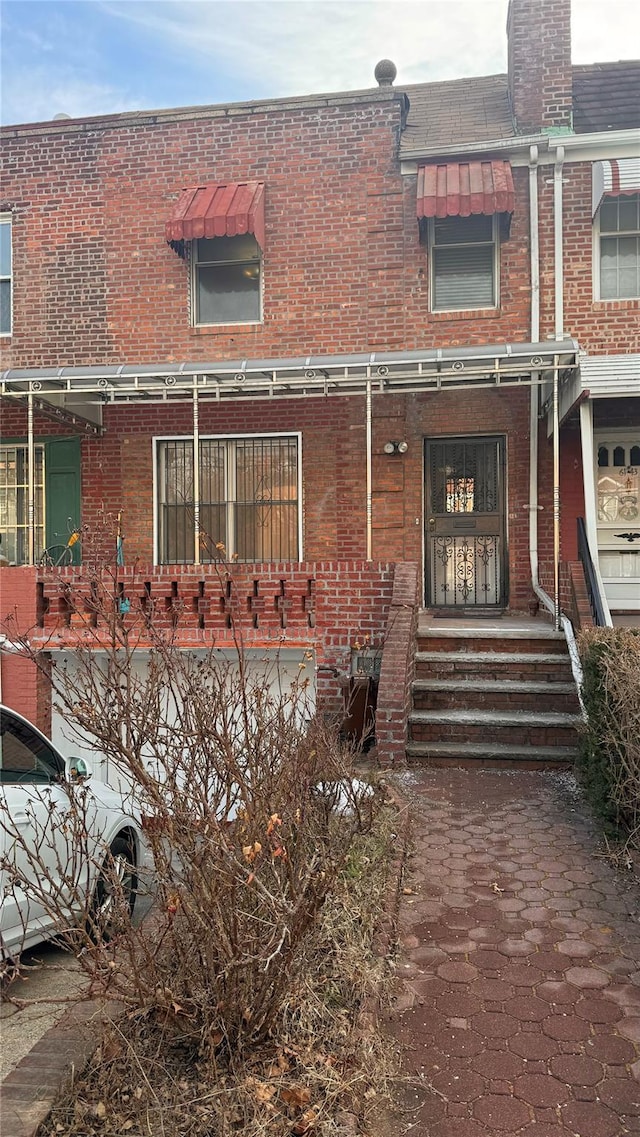 view of front of property with roof with shingles, mansard roof, and brick siding