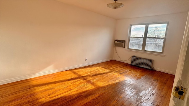 unfurnished room with light wood-type flooring, baseboards, radiator heating unit, and a wall mounted AC