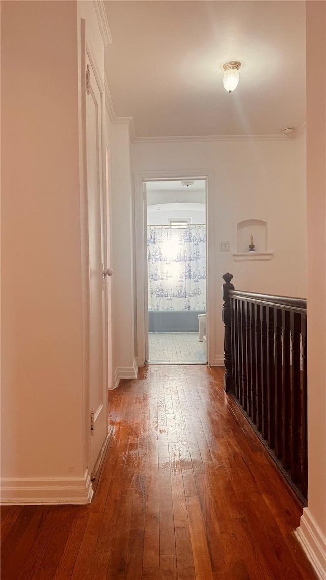 hallway with ornamental molding, dark wood finished floors, and baseboards