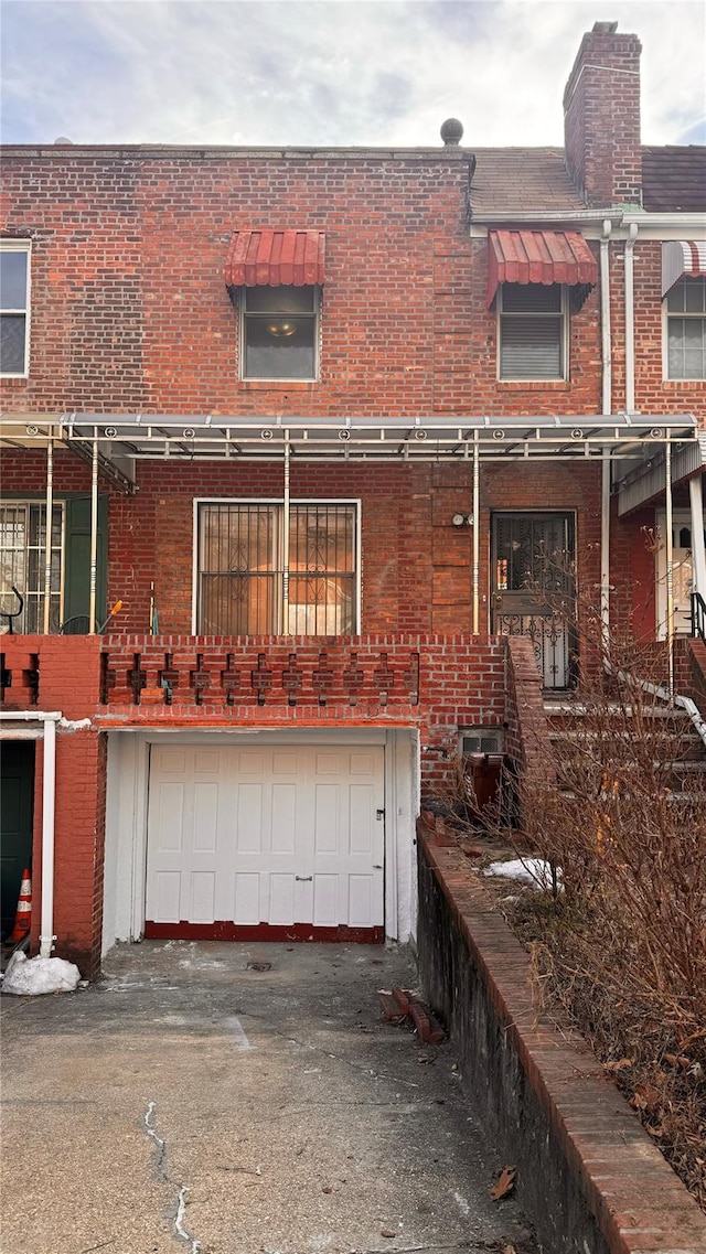 back of house with a garage, driveway, and brick siding