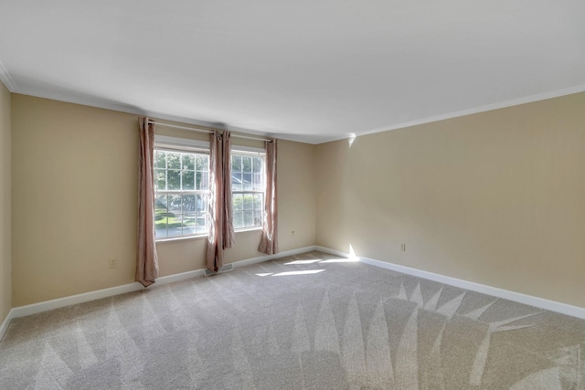 spare room with light carpet, baseboards, and crown molding