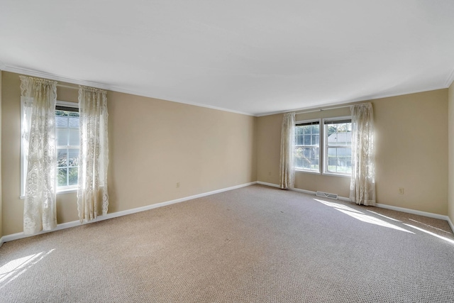 carpeted empty room featuring ornamental molding, visible vents, and baseboards