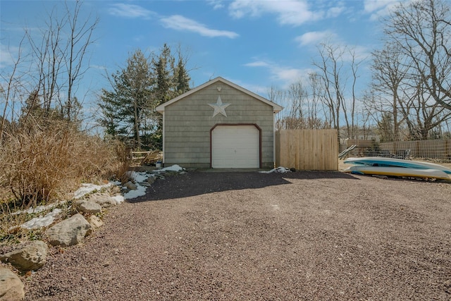 detached garage with gravel driveway and fence