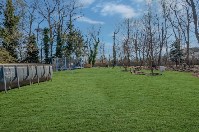 view of yard with a trampoline and a swimming pool