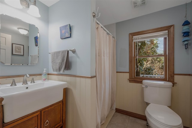 full bathroom with toilet, vanity, visible vents, and wainscoting