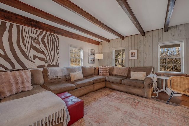 living area featuring beamed ceiling and wooden walls