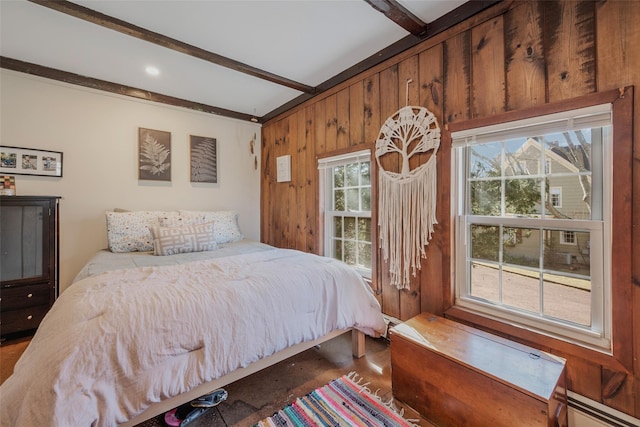 bedroom featuring a baseboard radiator, wooden walls, and beamed ceiling