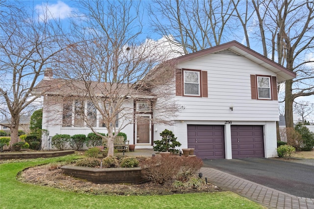 split level home featuring driveway, brick siding, and an attached garage