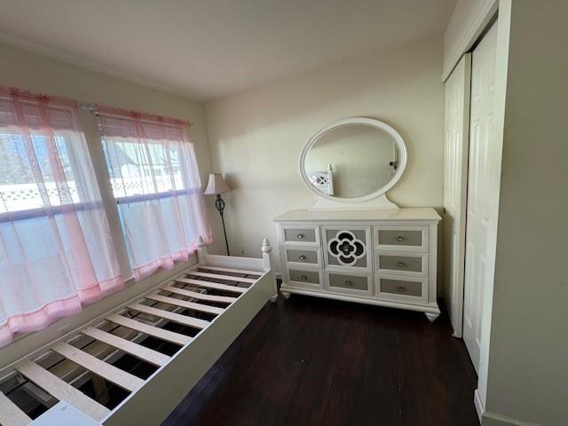 unfurnished bedroom with dark wood finished floors and a closet