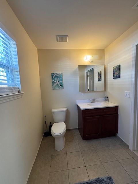 half bath with toilet, tile patterned flooring, visible vents, and vanity