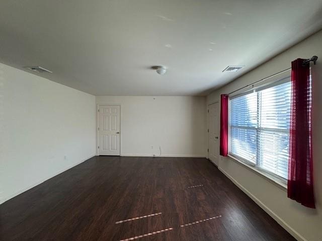 spare room featuring dark wood-style floors, baseboards, and visible vents