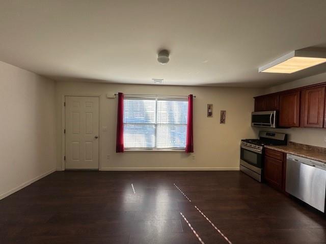 kitchen with appliances with stainless steel finishes, dark wood-style flooring, and baseboards