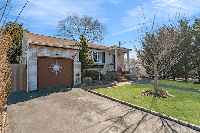 view of front of property with aphalt driveway, brick siding, an attached garage, fence, and a front lawn