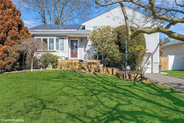 view of front of house with fence, solar panels, and a front yard