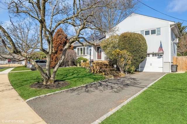 view of front of home featuring an attached garage, driveway, fence, and a front yard