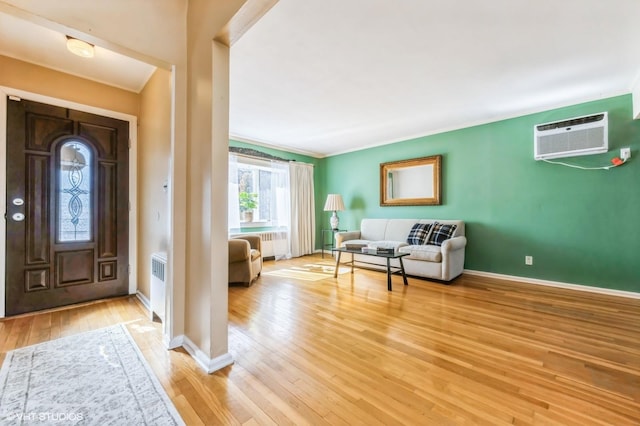 foyer entrance with light wood finished floors, radiator heating unit, and baseboards