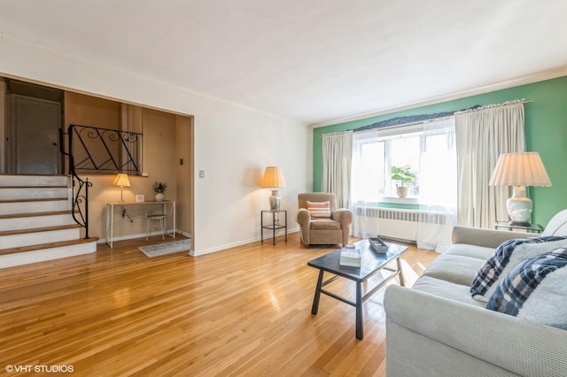 living area featuring baseboards, radiator heating unit, stairway, wood finished floors, and crown molding