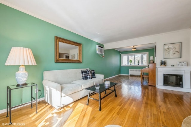 living room with a glass covered fireplace, baseboards, hardwood / wood-style floors, and radiator heating unit