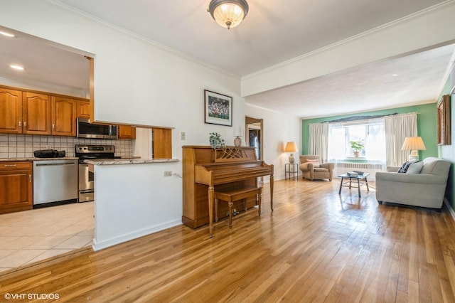 kitchen with stainless steel appliances, backsplash, brown cabinetry, open floor plan, and light wood-type flooring