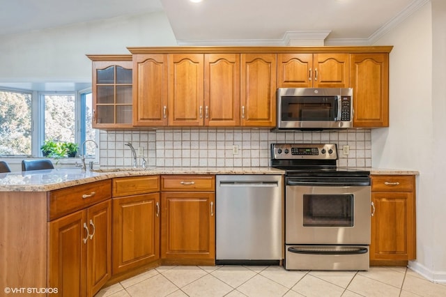 kitchen featuring stainless steel appliances, brown cabinets, and light stone countertops