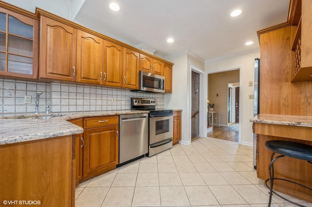 kitchen with appliances with stainless steel finishes, a sink, light stone counters, and tasteful backsplash