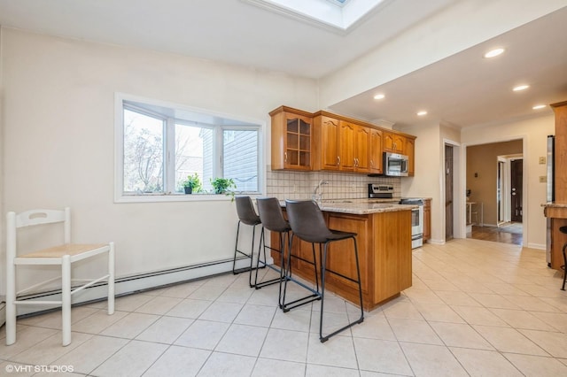 kitchen featuring a skylight, brown cabinetry, decorative backsplash, appliances with stainless steel finishes, and a peninsula