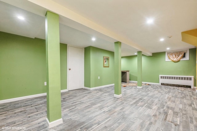 finished below grade area featuring recessed lighting, baseboards, radiator heating unit, and wood finished floors