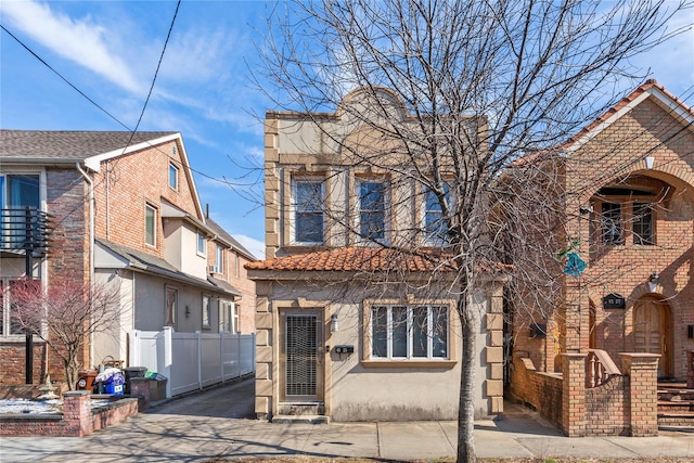 view of front of property with a tile roof, fence, and stucco siding