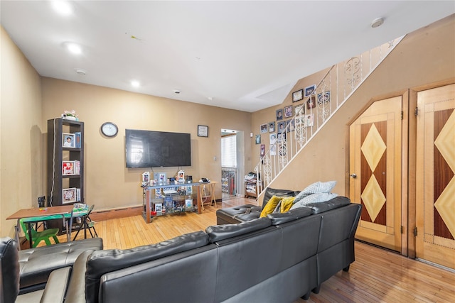 living room with hardwood / wood-style flooring, stairway, baseboards, and arched walkways