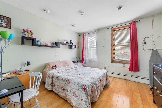 bedroom with light wood-style flooring and baseboard heating