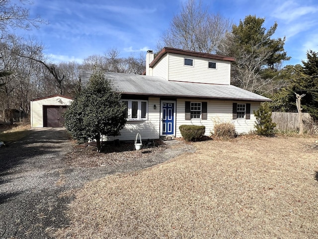 view of front of property with a garage, a chimney, fence, and an outbuilding