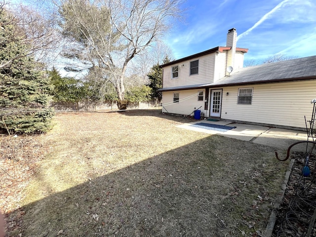 rear view of house with a yard, a chimney, a patio area, and fence