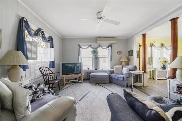 living area featuring a ceiling fan, radiator, ornamental molding, a wall mounted air conditioner, and ornate columns