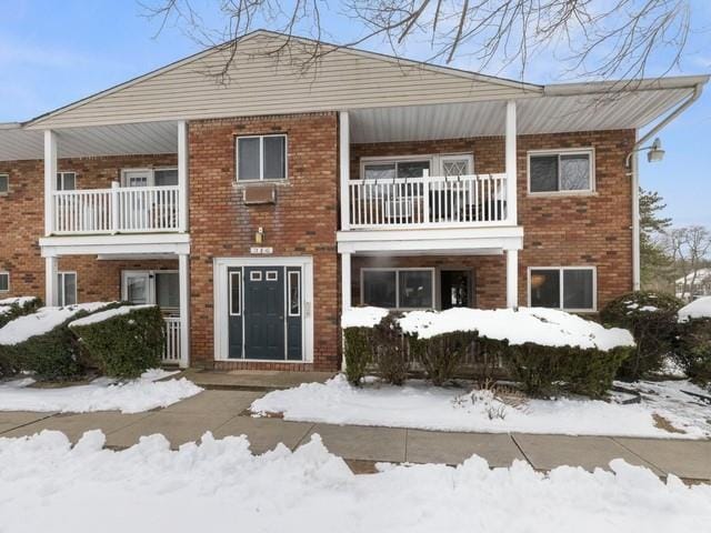 view of front of home with brick siding and a balcony