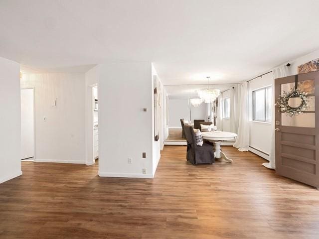 interior space featuring dark wood-style floors, baseboard heating, and an inviting chandelier