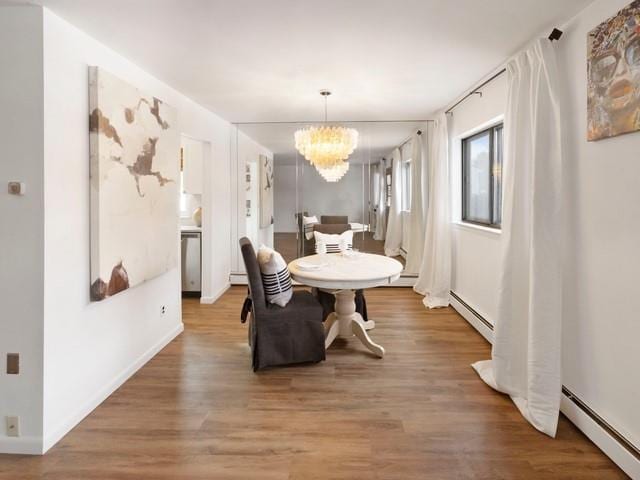 dining space featuring a baseboard radiator, light wood-style flooring, and a notable chandelier