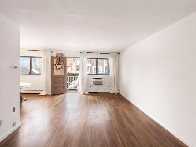 unfurnished living room featuring baseboards, baseboard heating, and wood finished floors