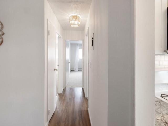 hallway featuring dark wood-style floors and baseboards