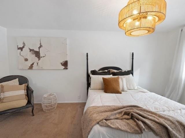 carpeted bedroom with baseboards and a notable chandelier