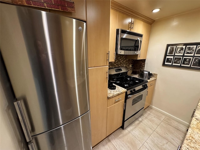 kitchen featuring light stone counters, light brown cabinets, baseboards, appliances with stainless steel finishes, and decorative backsplash