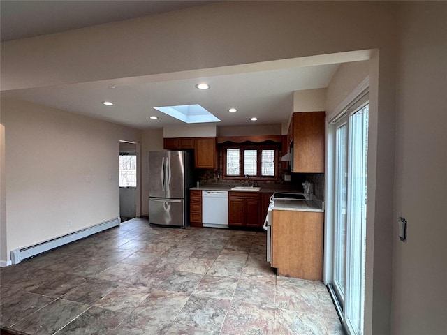 kitchen featuring a skylight, a baseboard radiator, freestanding refrigerator, white dishwasher, and range with electric cooktop