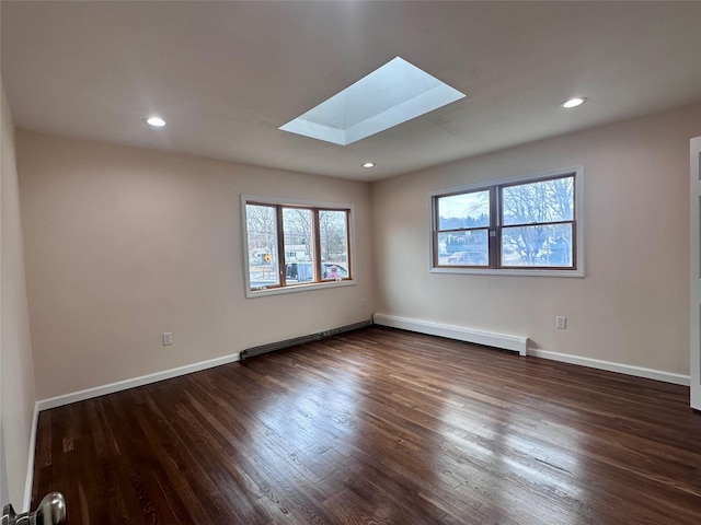 empty room with a skylight, baseboards, a baseboard heating unit, and dark wood finished floors