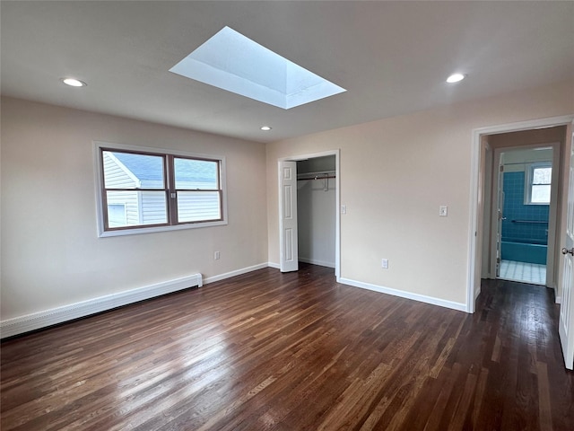 unfurnished bedroom with a baseboard radiator, a skylight, dark wood finished floors, and baseboards