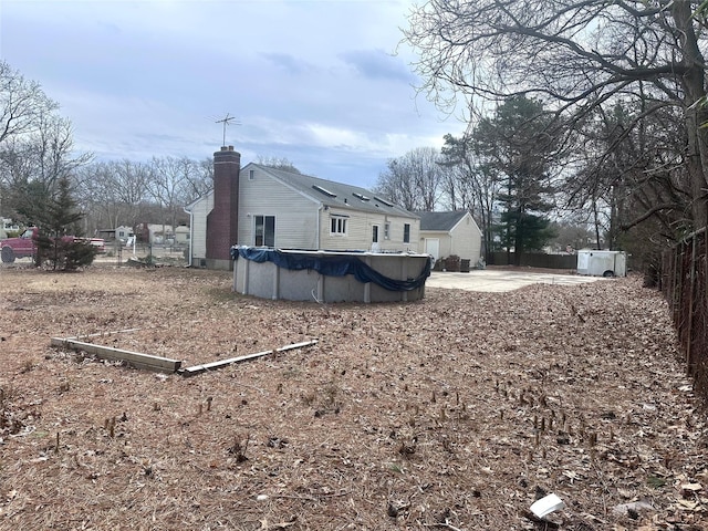 view of home's exterior with a patio area, a covered pool, fence, and a chimney