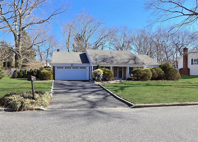 view of front of house featuring an attached garage, driveway, a chimney, and a front yard